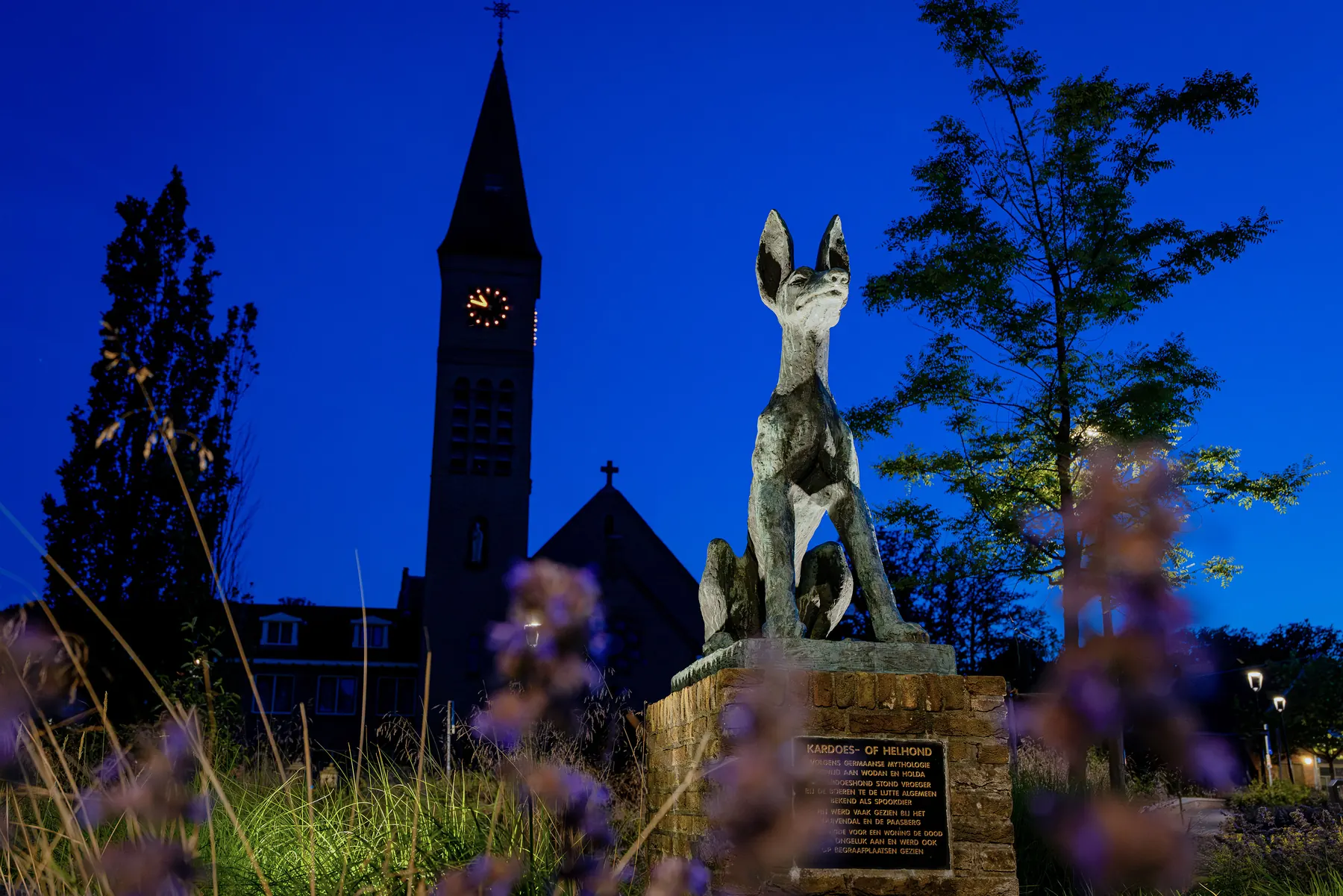 Plechelmuskerk en standbeeld bij avond